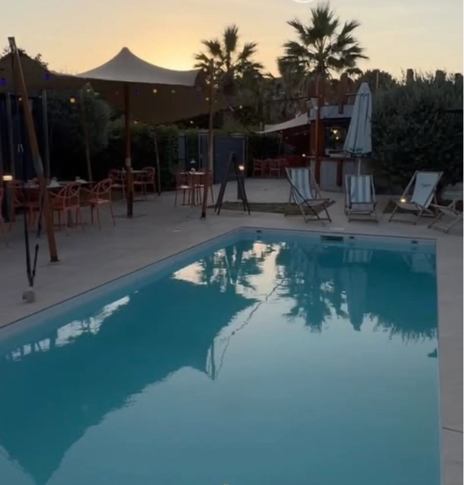 Piscine et terrasse d'AZÙRA by Terre et Mer à Labège au coucher du soleil, transats, parasols et palmiers